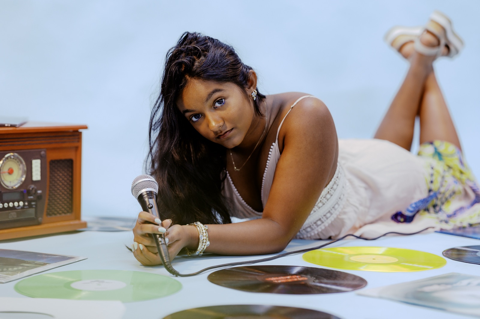 Anya lying among vinyl records holding a microphone