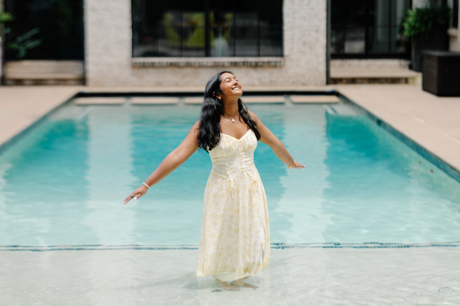 Anya with arms outstretched, face to the sun, standing in a pool
